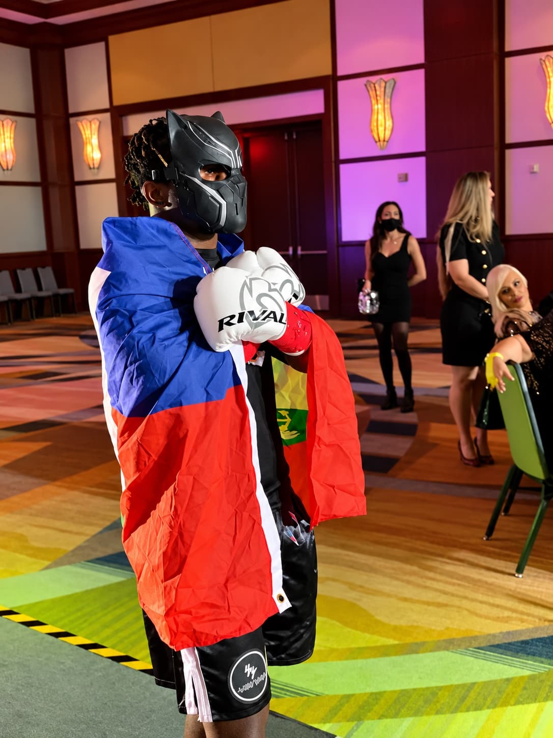 Kenneth Sene in a black mask with the Haitian flag over his shoulders before a fight