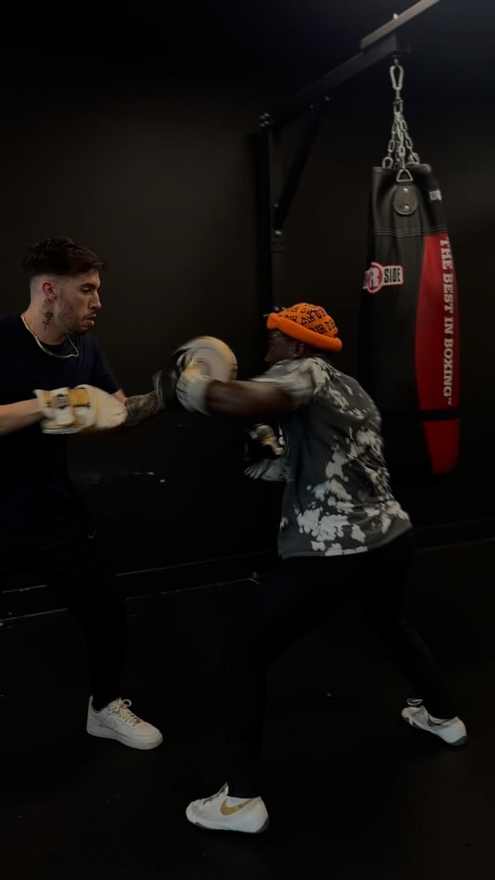 Kenneth Sene working combinations on the mitts in a dark boxing gym